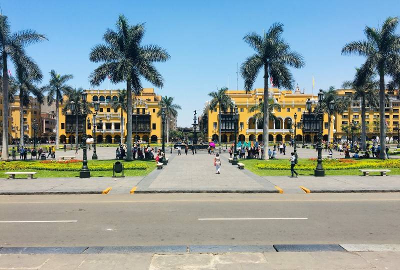 Plaza Mayor in Lima, Peru with yellow colonial buildings and palm trees.
