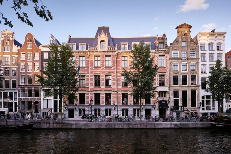 A picturesque canal-side hotel in Amsterdam with bicycles lined up in front.
