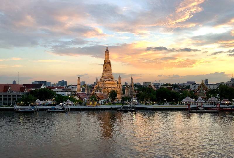Templo Wat Arun às margens do rio Chao Phraya ao pôr do sol em Bangcoc.