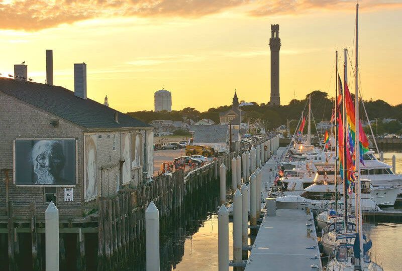 Um pôr do sol sobre um porto em Provincetown com um píer e barcos