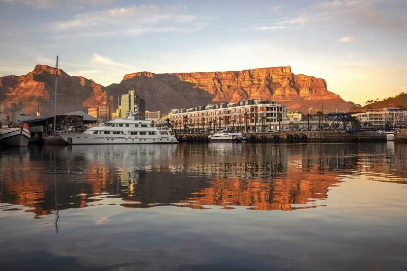 A waterfront scene with yachts docked near Table Mountain in Cape Town.