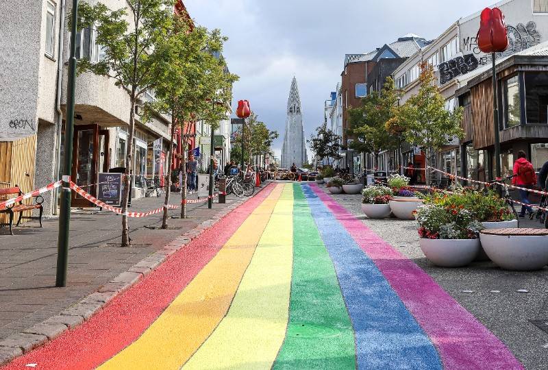 Rua pintada com arco-íris em Reykjavik com Hallgrímskirkja à vista.