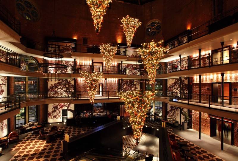 A stylish hotel atrium with warm lighting and upside-down illuminated Christmas trees.