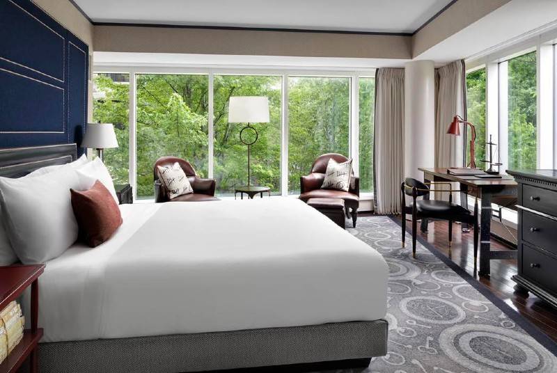 A luxurious bedroom with a canopy bed, wooden flooring, and an outdoor lounging area.